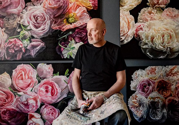 Robert Lemay sitting in front of his artwork
