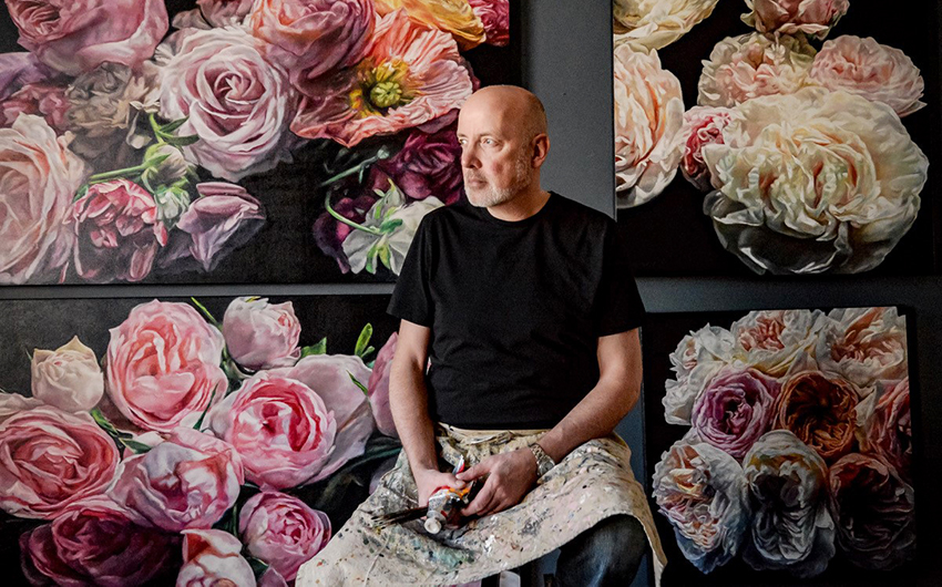 Robert Lemay sitting in front of his artwork