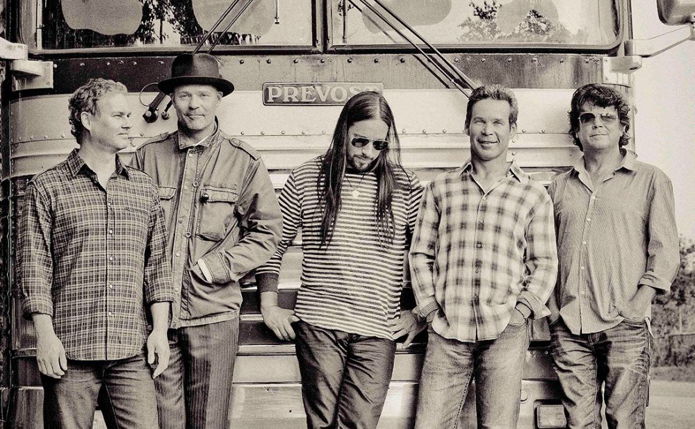 The Tragically Hip band members standing in front of bus.