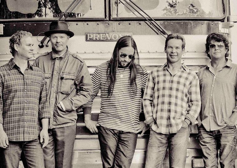 The Tragically Hip band members standing in front of bus.