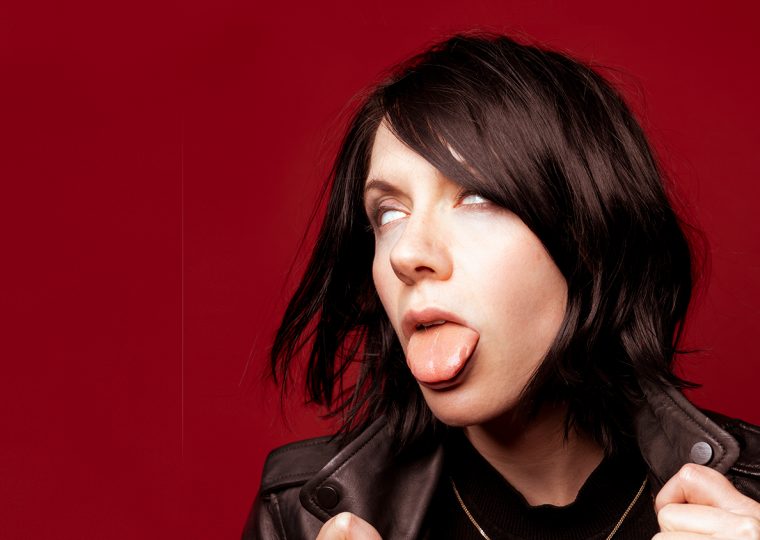 K.Flay posing in leather jacket, rolling her eyes back and sticking out her tongue