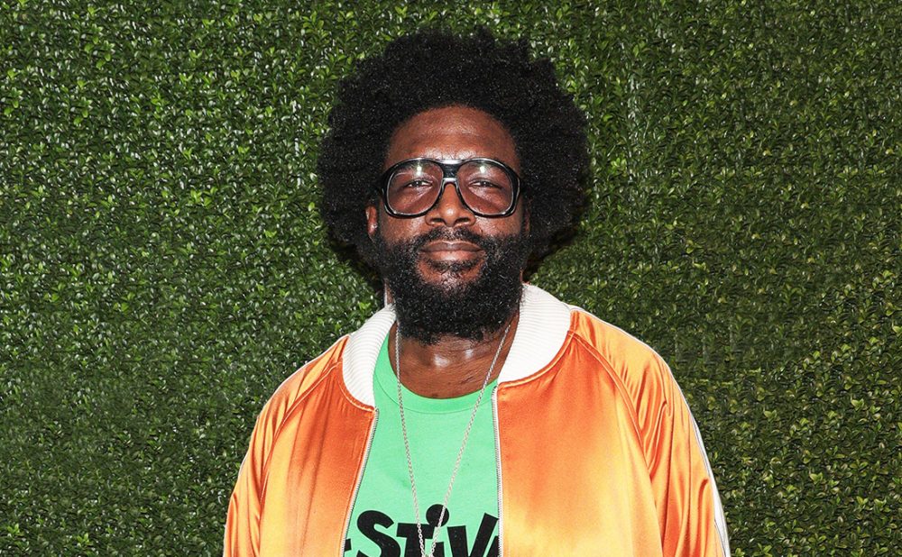 Questlove posing in front of green wall