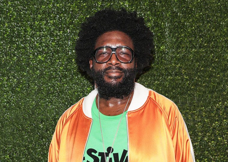 Questlove posing in front of green wall