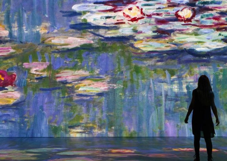 Silhouette of person standing in front of projected Monet painting