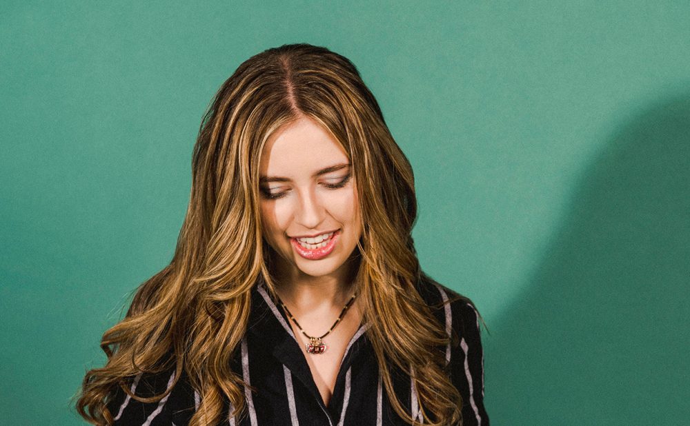 Ayla posing in front of green wall