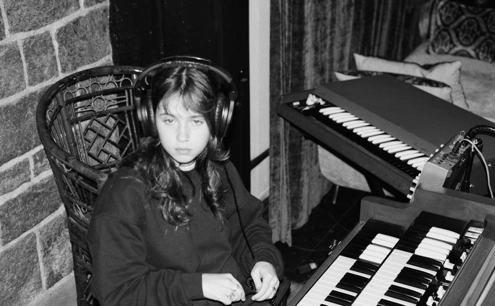 Clairo sitting at piano in recording studio