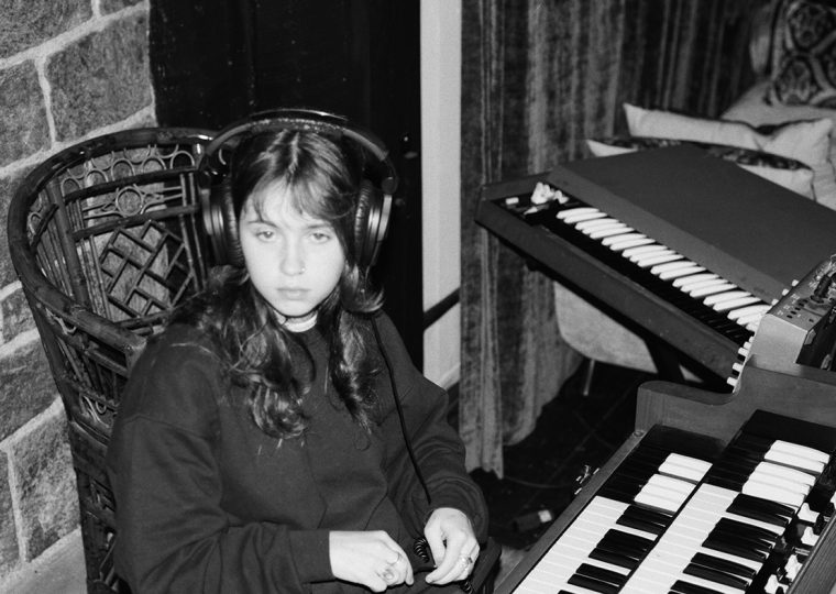 Clairo sitting at piano in recording studio