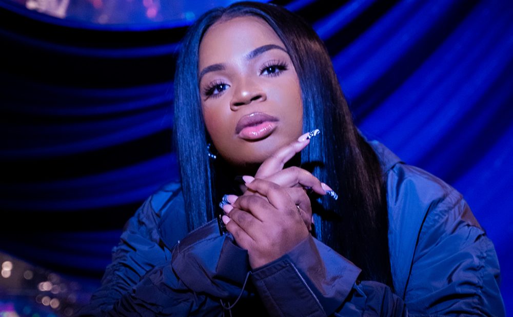 Savannah Re posing in front of draped blue fabric.