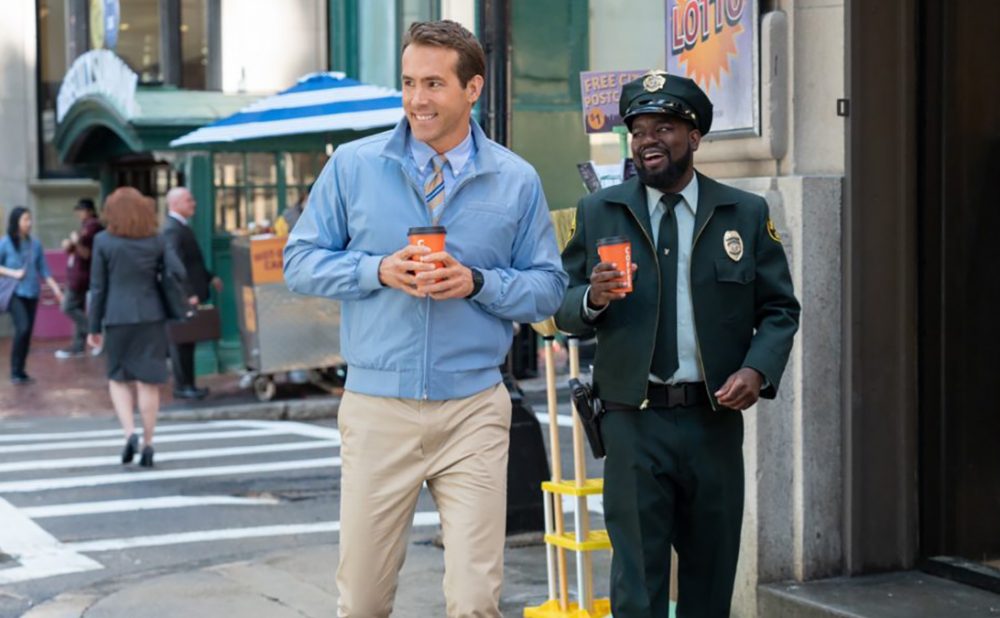 Ryan Reynolds and Lil Rel Howery walking down the street with coffees.