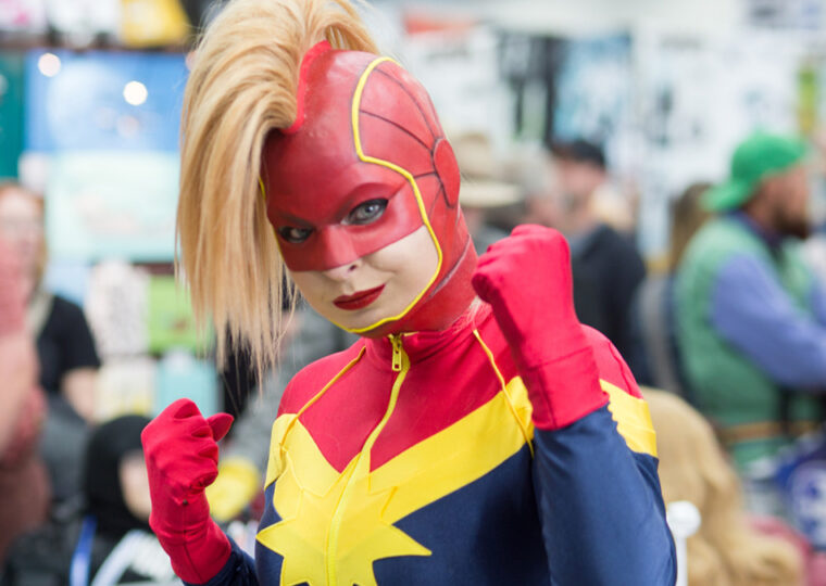 A woman dressed up in Captain Marvel cosplay at a comic expo.