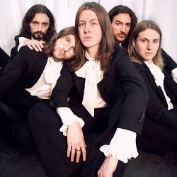 Five men seated closely together, wearing white and black.