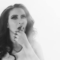 Kayla Diamond shot in black and white, wiping her lips with her thumb.