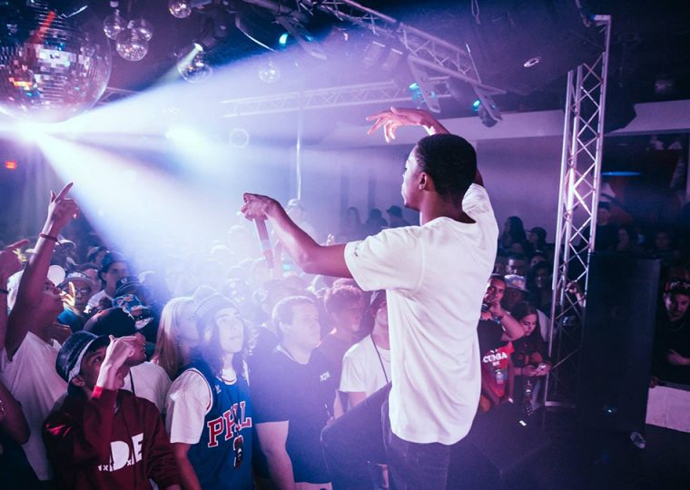 A man performing on stage to a packed crowd.