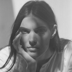 Black and white photo of Charlotte Cardin with her head resting in her hand.