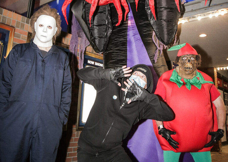 Three people dressed in Halloween costumes outside a movie theatre