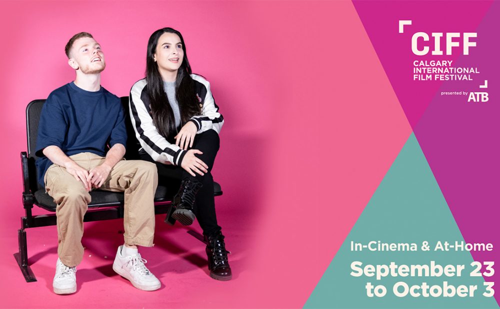 A man and woman sitting on a bench against a pink backdrop, promoting the Calgary International Film Festival.