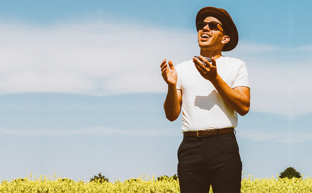 Jeremie Albino standing in a field of yellow flowers looking up.