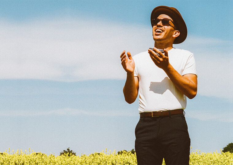 Jeremie Albino standing in a field of yellow flowers looking up.