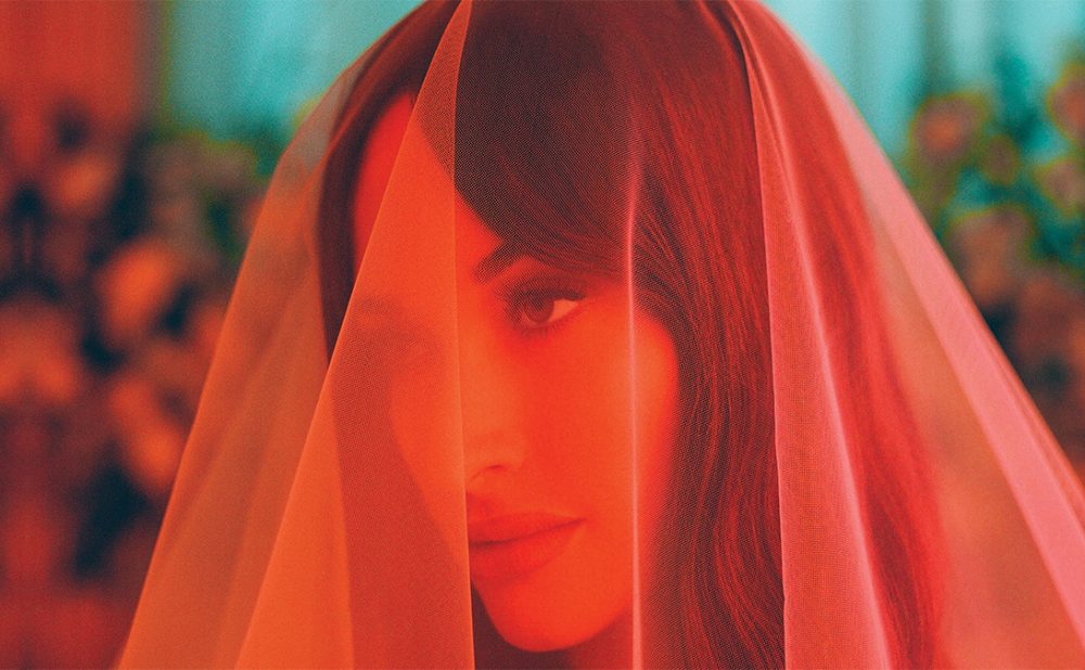 Kacey Musgraves with a veil fabric draped over her head.
