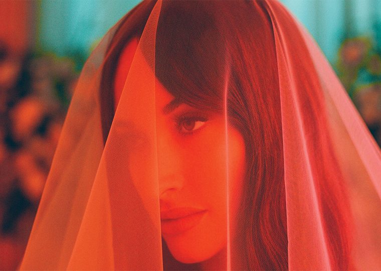 Kacey Musgraves with a veil fabric draped over her head.