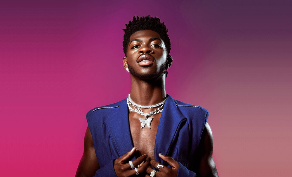 Lil Nas X posing against a pink gradient backdrop