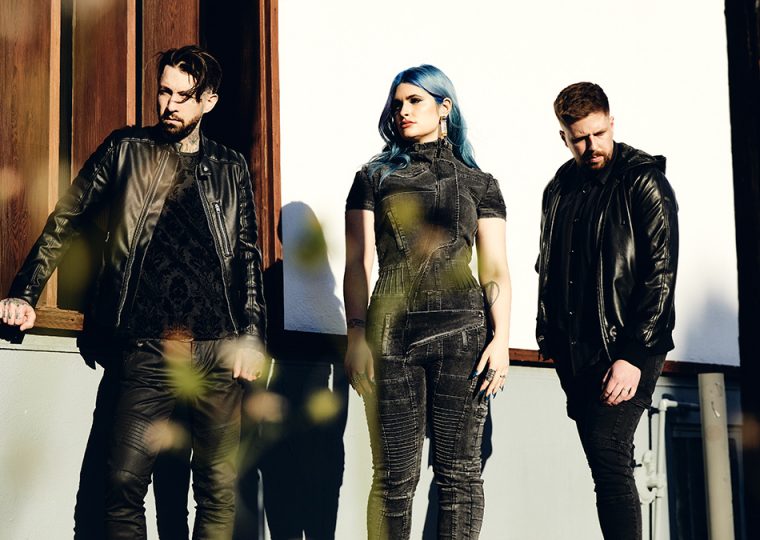 Bill Crook, Courtney LaPlante and Mike Stringer of Spiritbox standing outside, dressed in black.