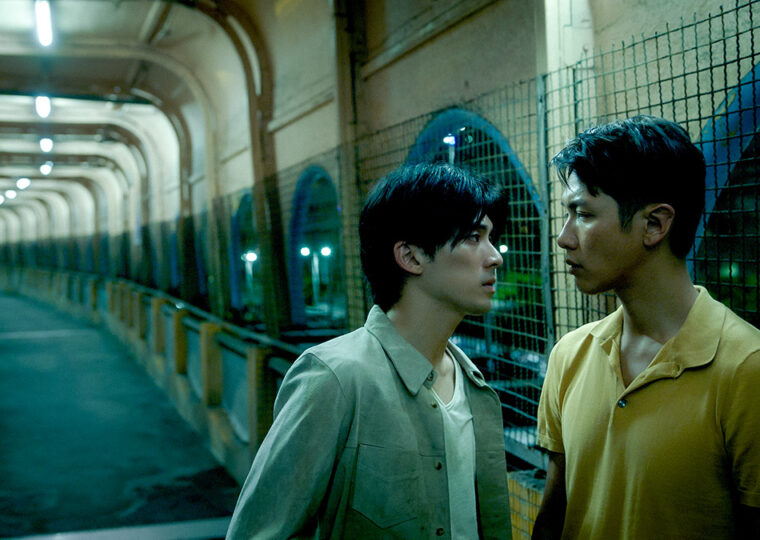 Still from the film Moneyboys of two men facing each other down a long expansive hall.