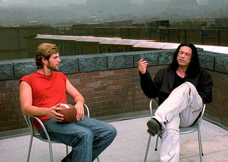 A scene from The Room with two characters sitting in chairs on a rooftop.