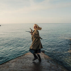 A woman at the water's edge, turning toward the camera