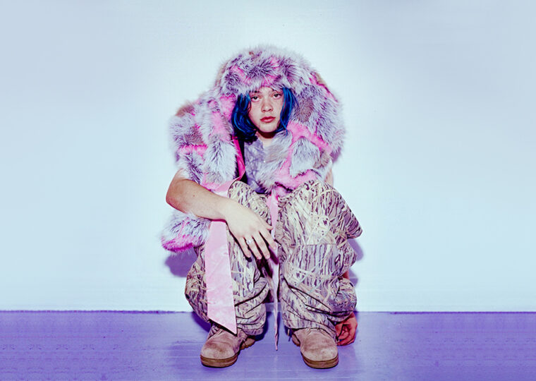 347aidan posing in a squat against a light background, on a lavender coloured floor.