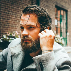 Theo Tam facing away from the camera wearing a grey coat outside.