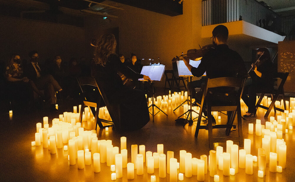 A string ensemble performing completely surrounded by candles on the floor.