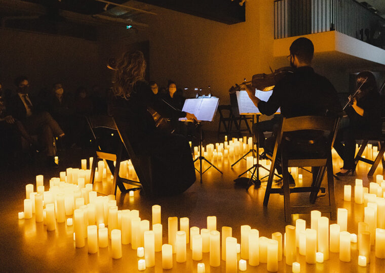 A string ensemble performing completely surrounded by candles on the floor.