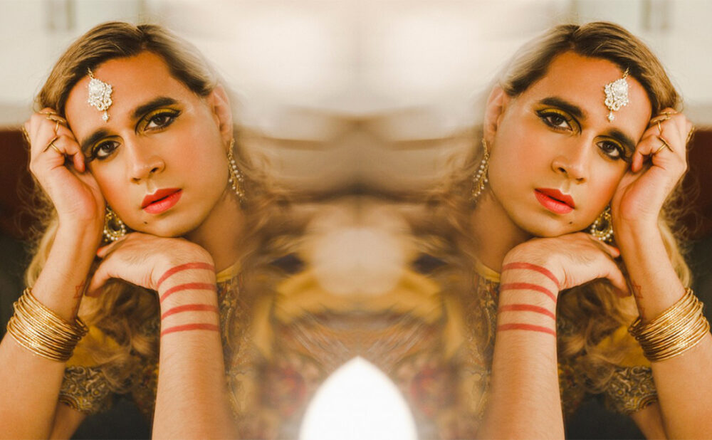 Vivek Shraya headshot, resting head on the back of the hand looking at the camera.