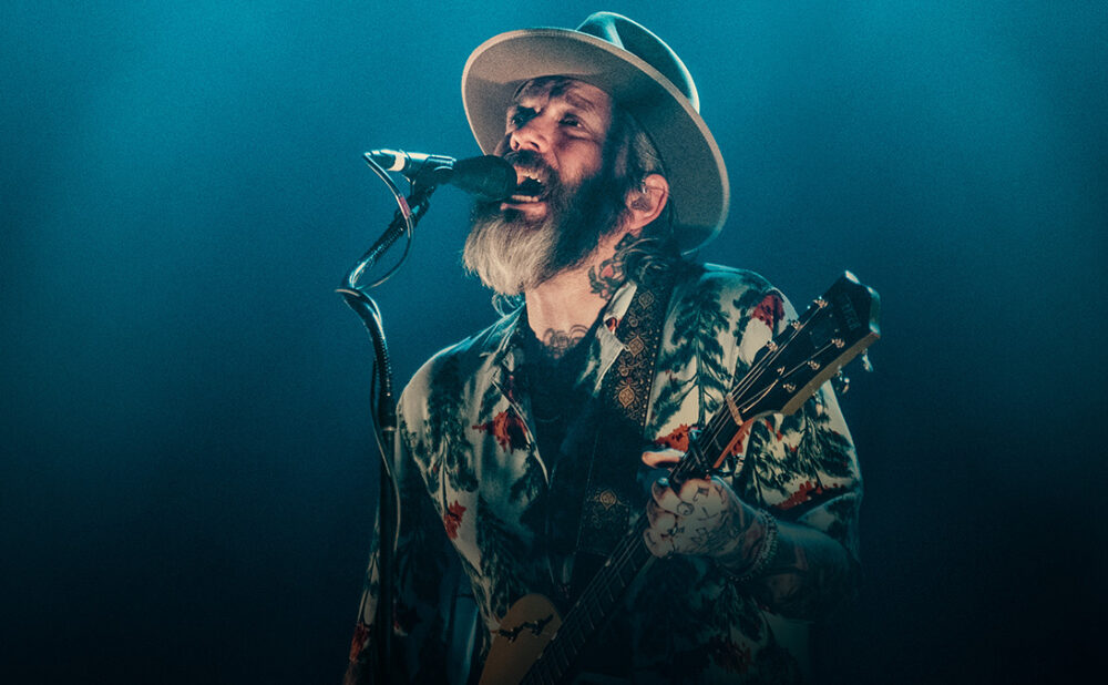 Dallas Green singing and playing guitar on stage.