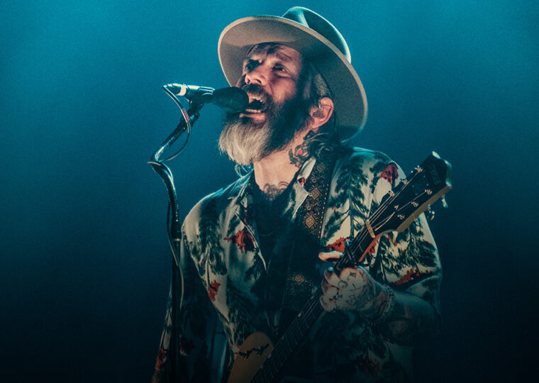 Dallas Green singing and playing guitar on stage.