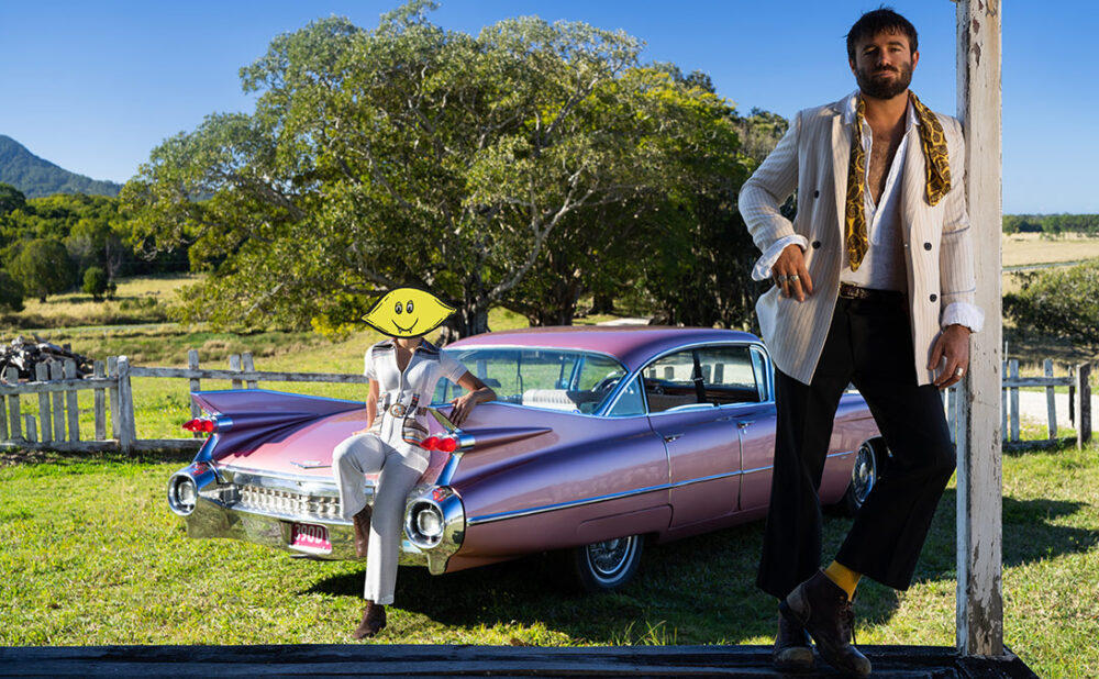 Dope Lemon standing in front of a rose pink cadillac.