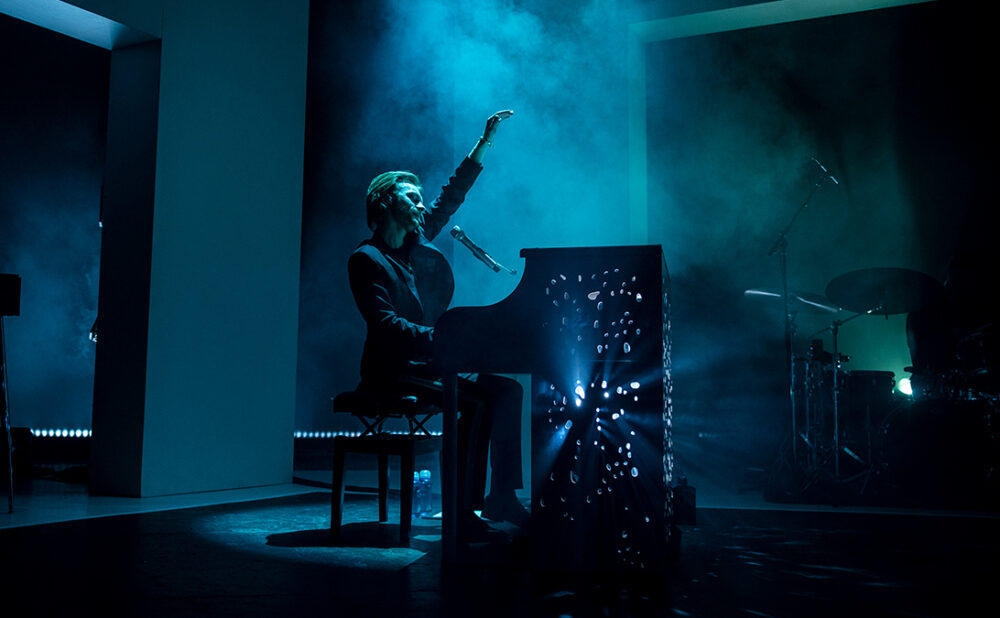 Finneas playing a piano and singing on stage at his Toronto show.