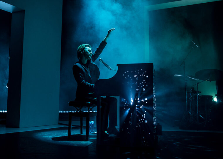 Finneas playing a piano and singing on stage at his Toronto show.